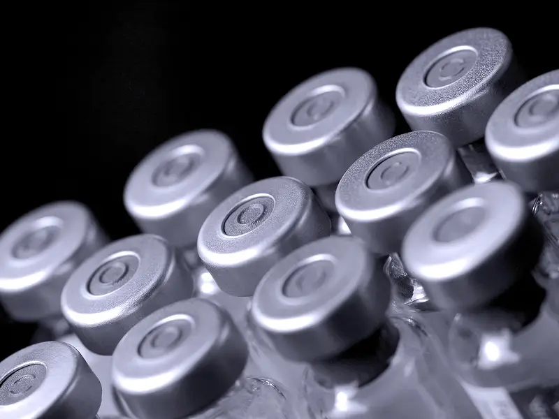 Close-up of sterile glass laboratory vials used for storing lyophilized research compounds on a dark surface.